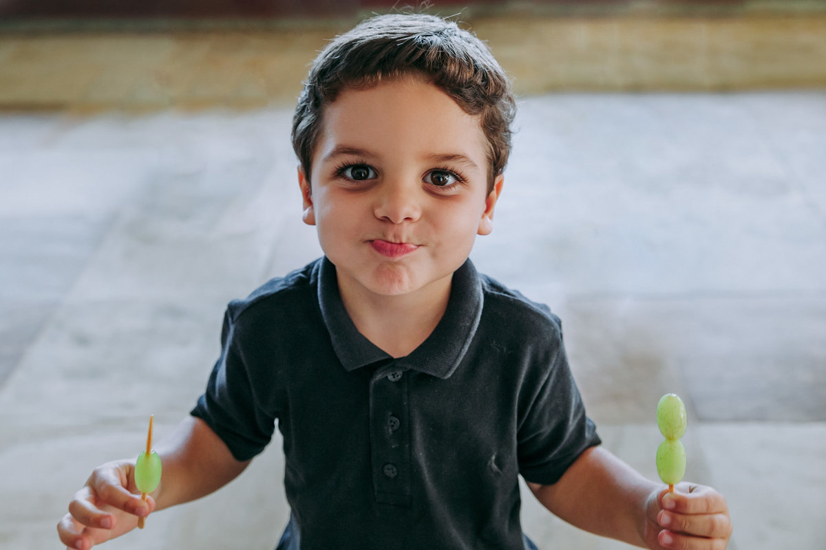 Fotografia de menino comendo uva em sua festa de aniversário no Rio de Janeiro