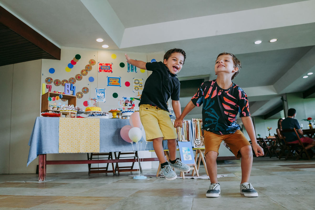 Fotografia de irmãos pulando na festa de aniversário deles