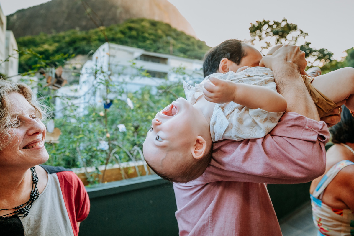 Fotografia de aniversariante as gargalhadas no colo do pai