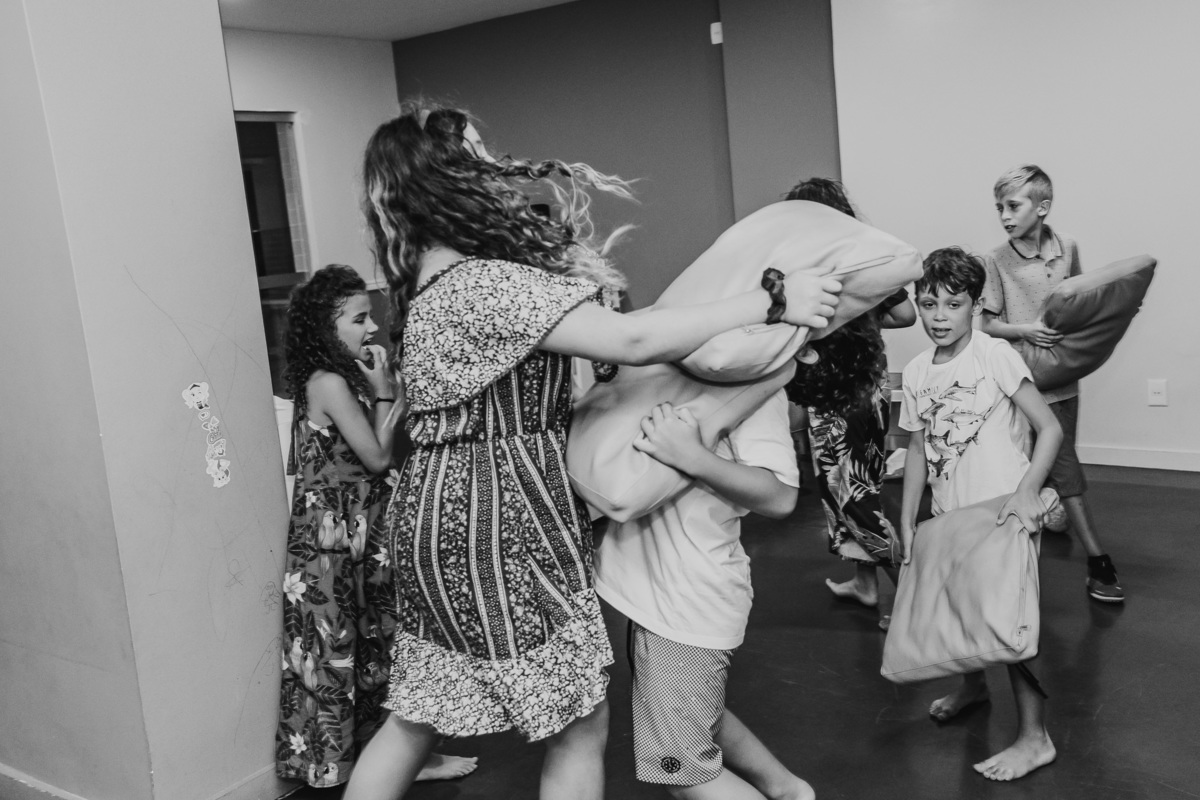Fotografia  preto e branco de crianças fazendo guerra de travesseiro