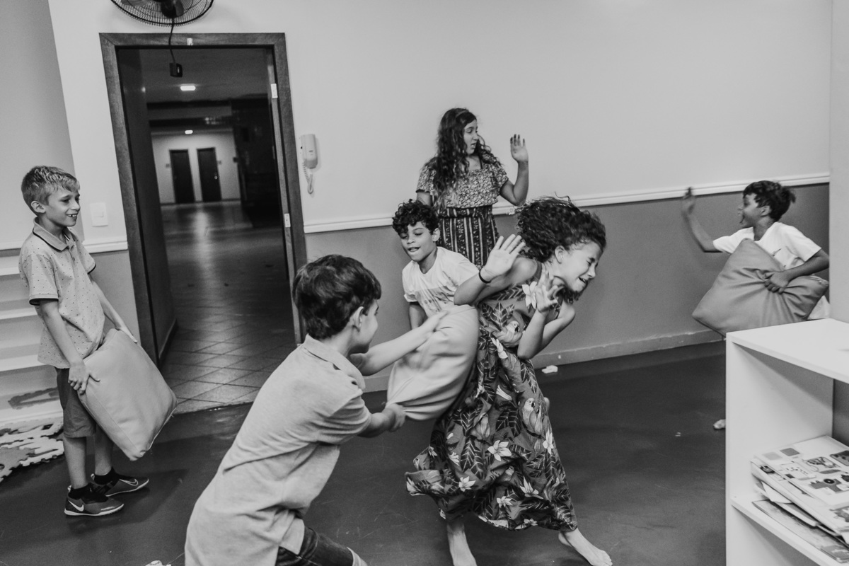 Fotografia preto e branco de menino jogando o travesseiro numa menina