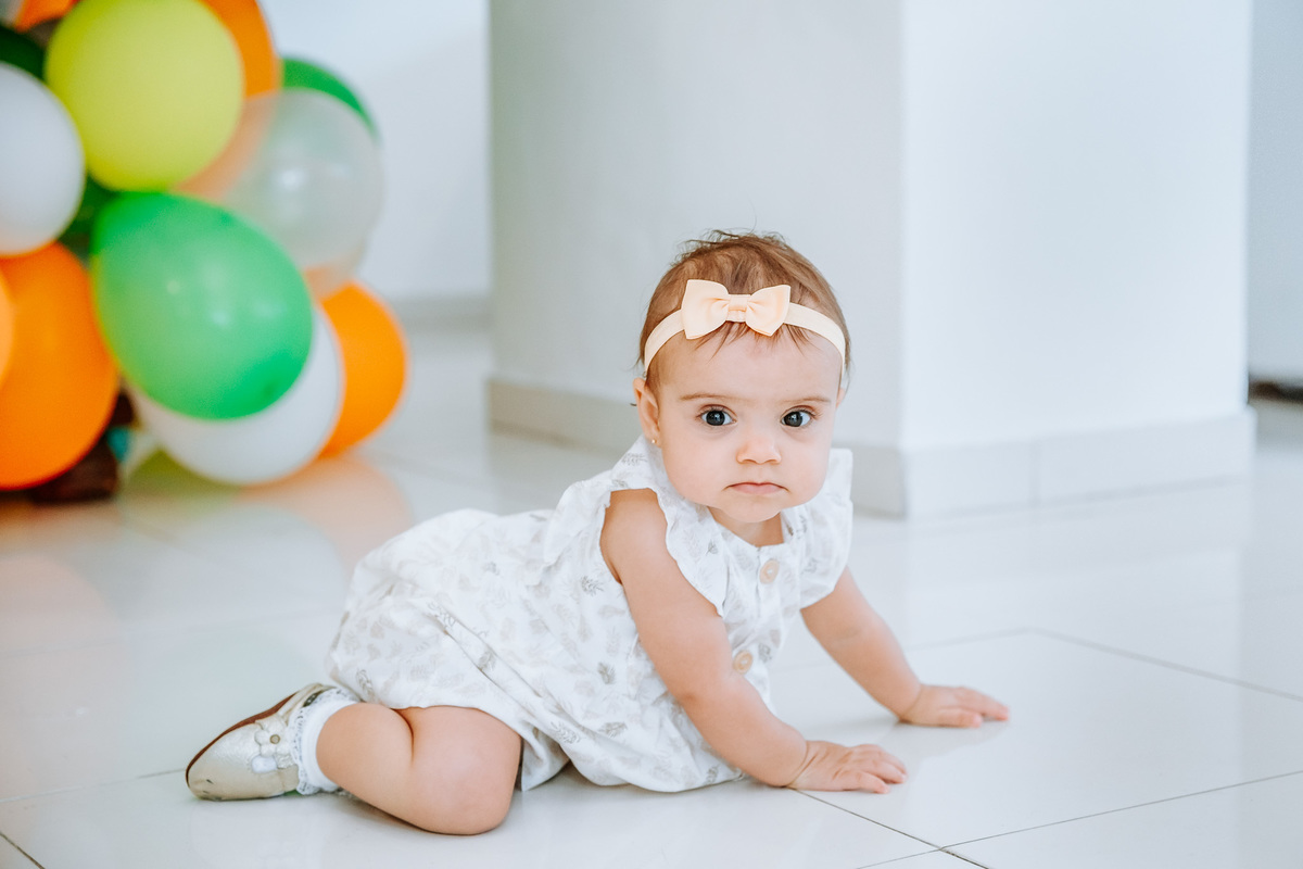 Fotografia de menina de 1 ano em sua festa de aniversário olhando pra camera