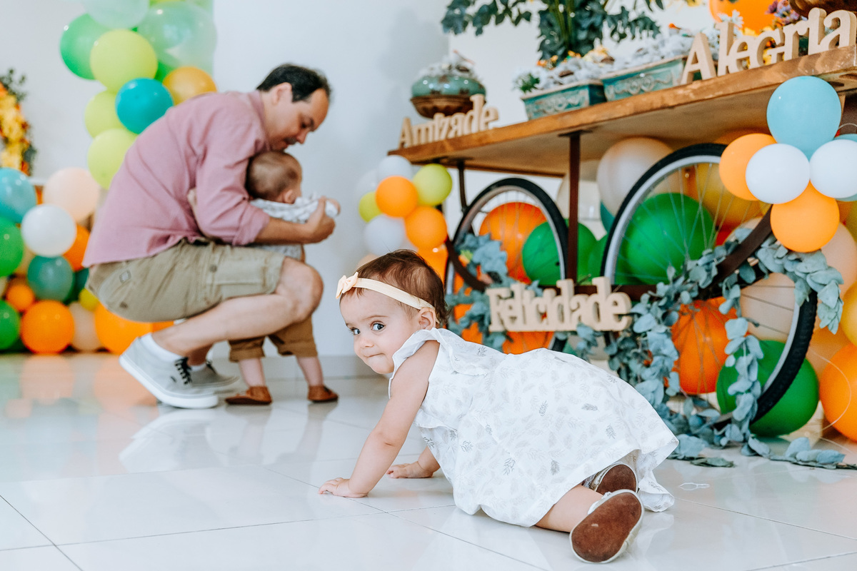 Fotografia de menina de 1 ano engatinhando em sua festa de aniversário