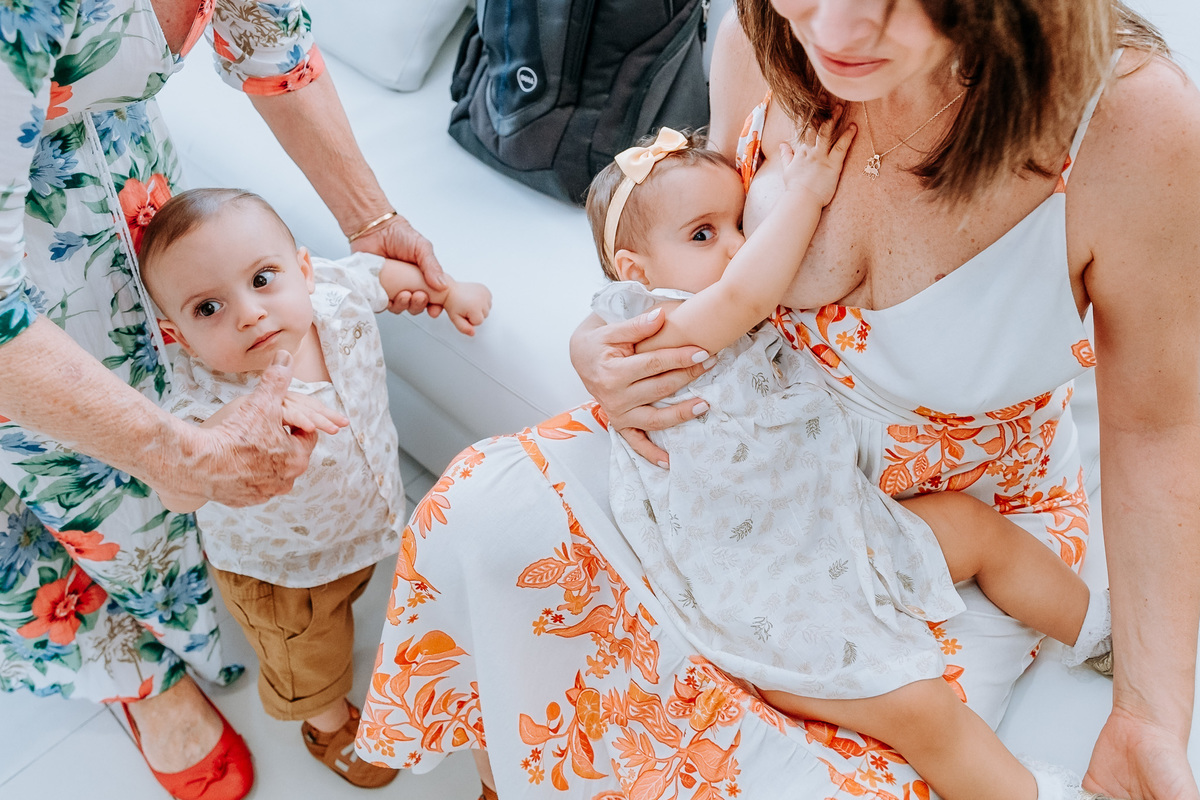 Fotografia de mãe e seus filhos gêmeos um mamando e o outro esperando