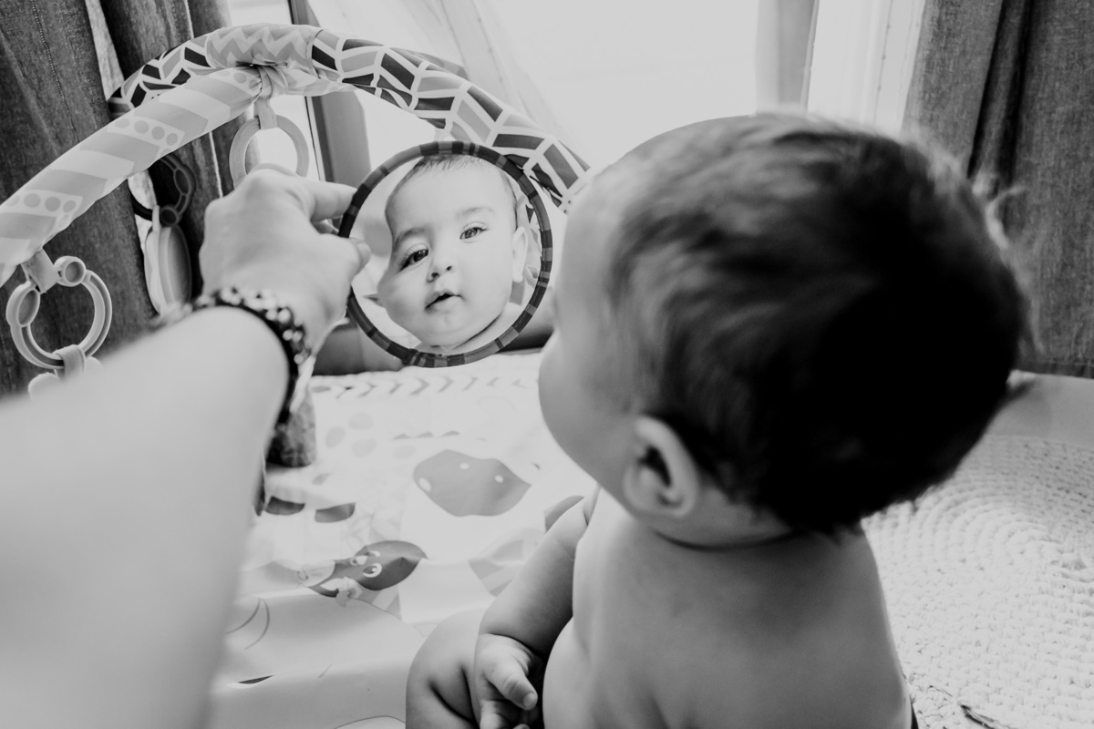 Fotografia de bebê se descobrindo em reflexo de brinquedo
