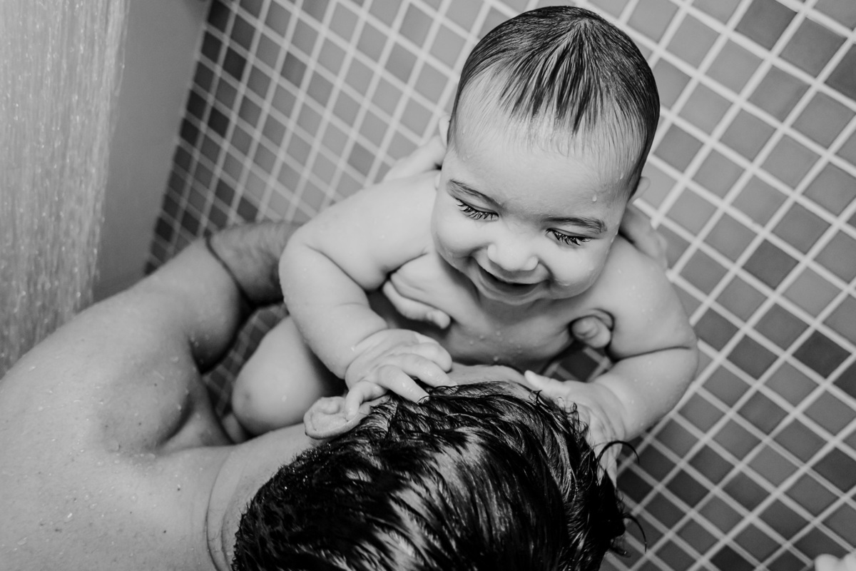 Fotografia de ensaio lifestyle com  bebê brincando com o pai no banho