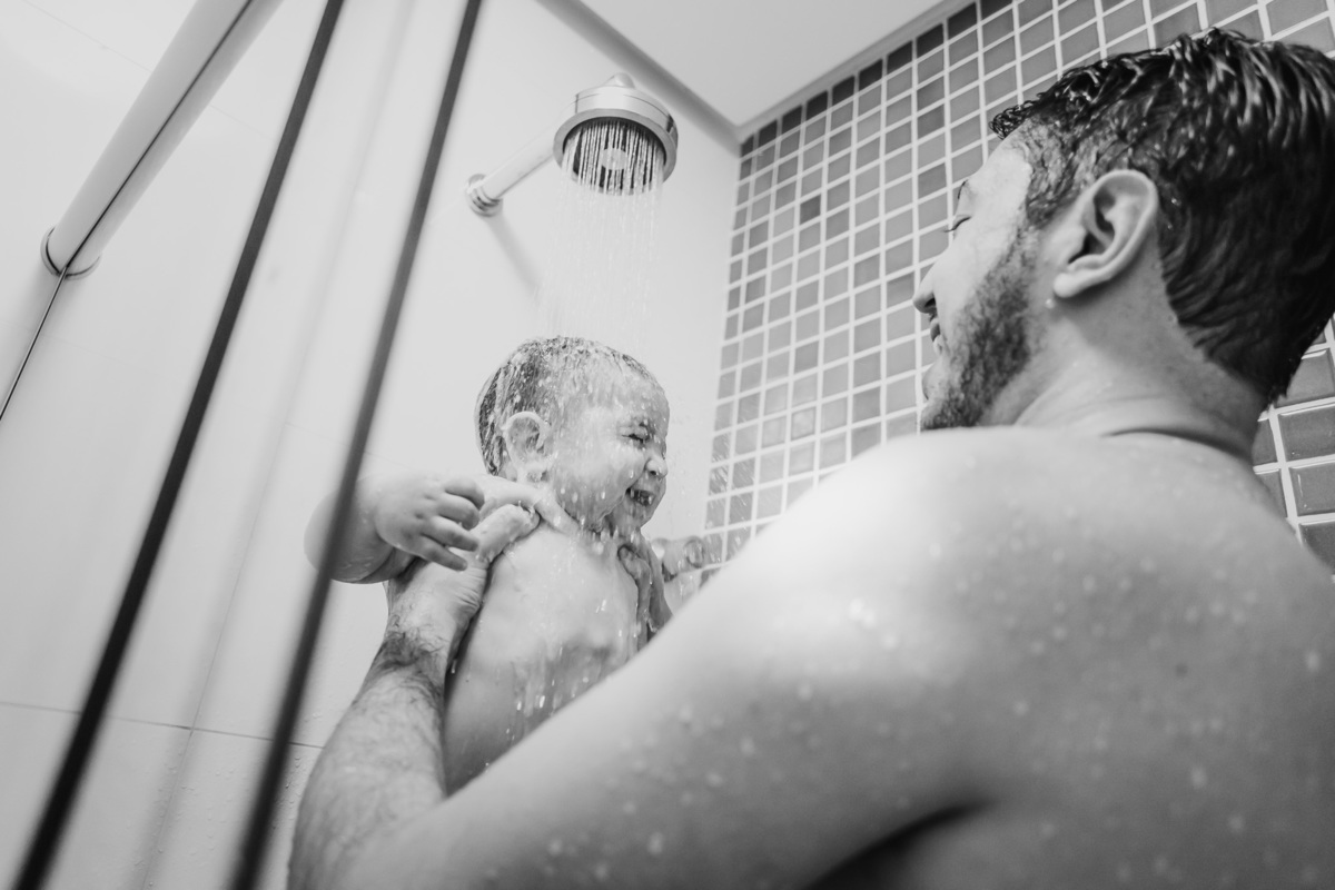 Fotografia de ensaio de família lifestyle com bebê brincando com o pai no banho