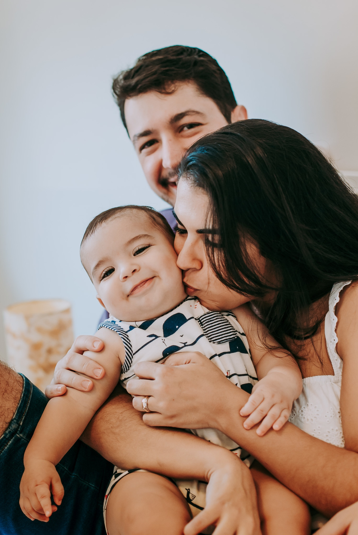 Fotografia de criança sorrindo ao receber beijo da mãe