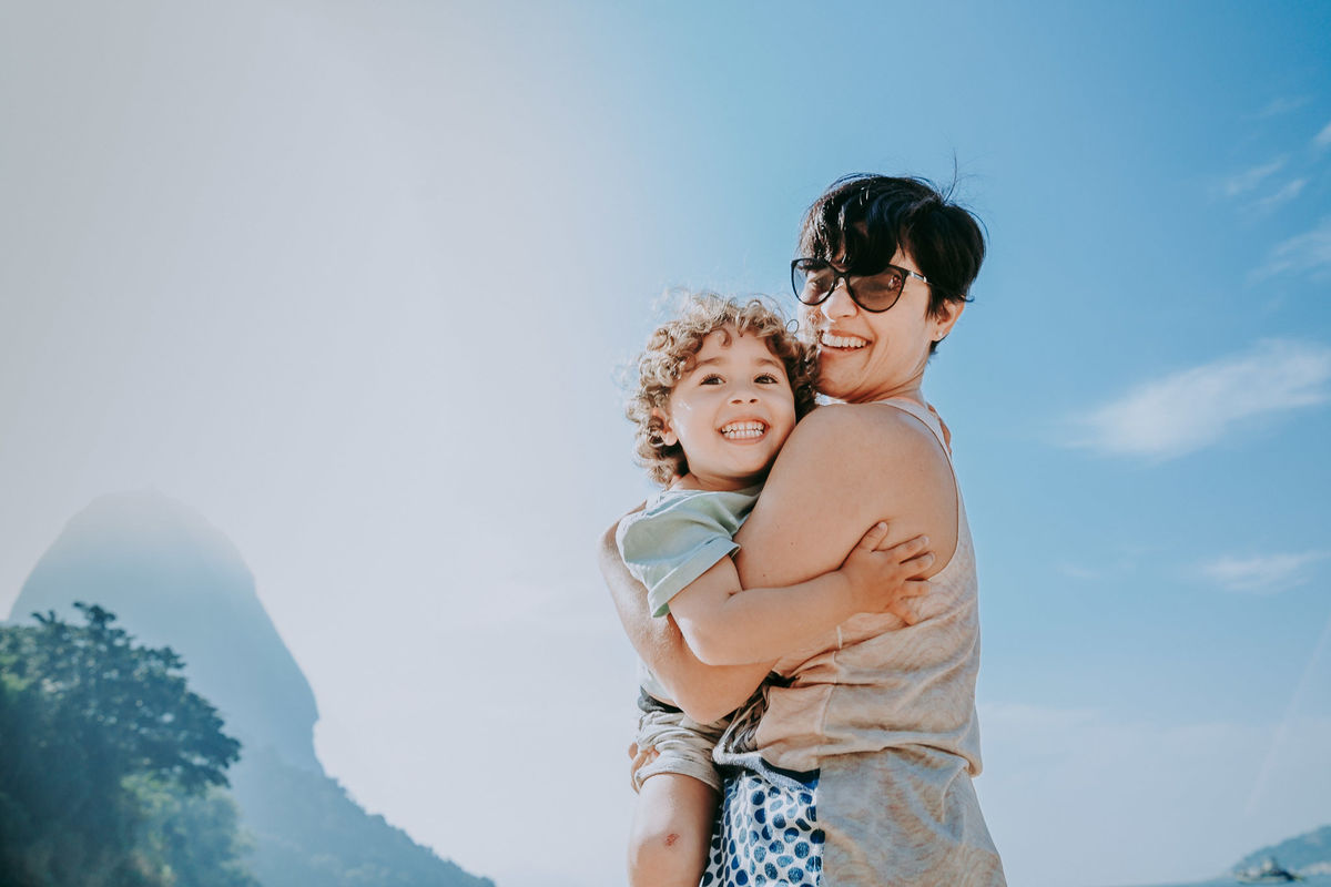 Fotografia de mãe e filho olhando para a câmera durante ensaio fotográfico na Praia Vermelha no RJ