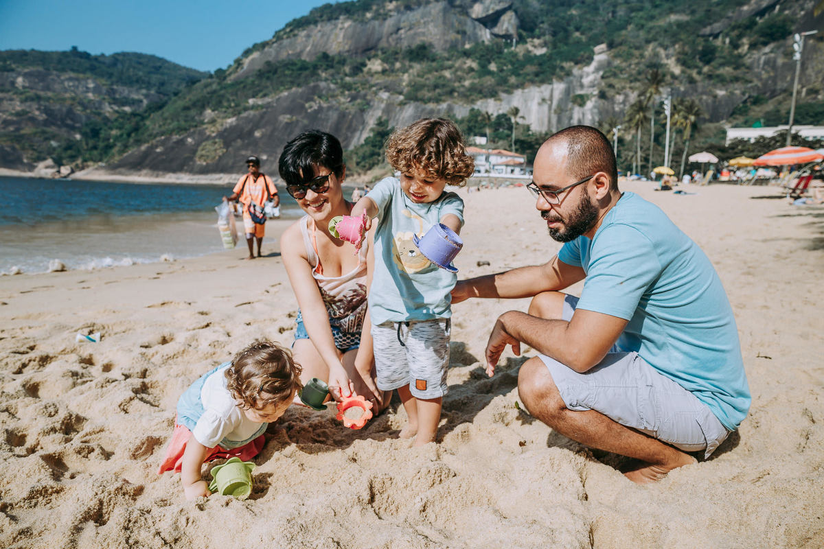 Fotografia de família  brincando na areia da Praia Vermelha no RJ durante ensaio fotográfico