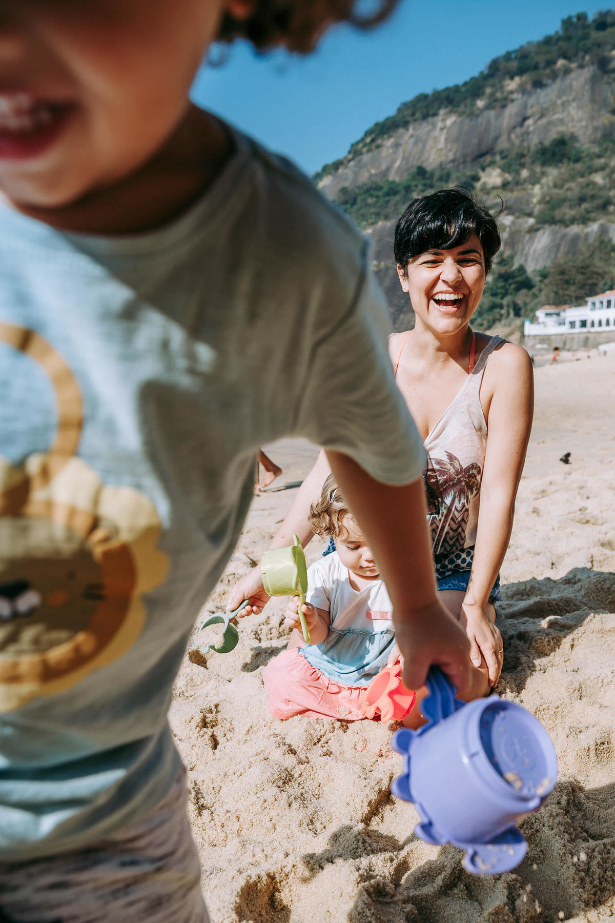 Fotgrafia de mãe gargalhando durante brincadeira do filho na areia da Praia Vermelha no RJ