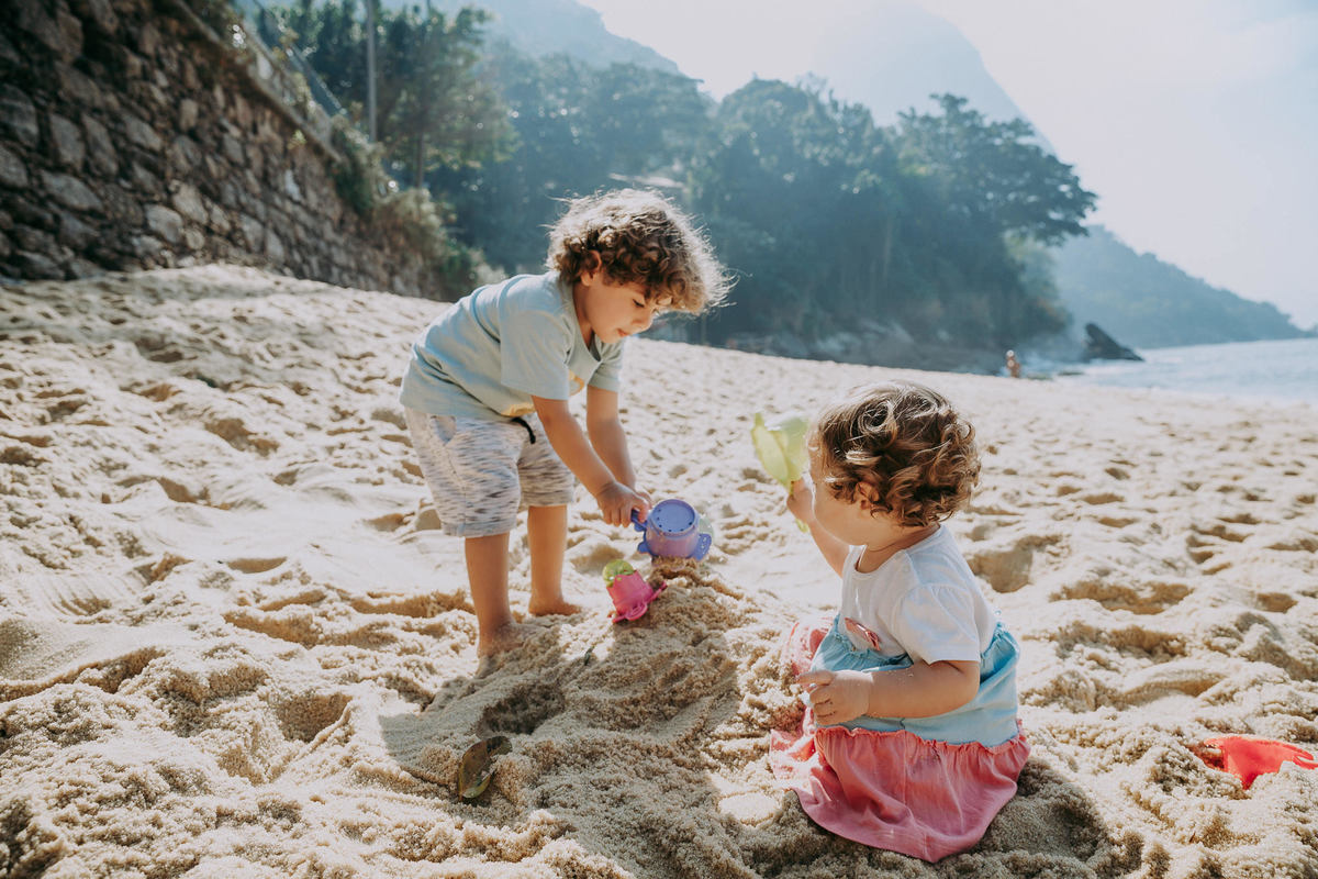 Fotografia de irmãos brincando na areia da Praia Vermelha no RJ durante ensaio fotográfico