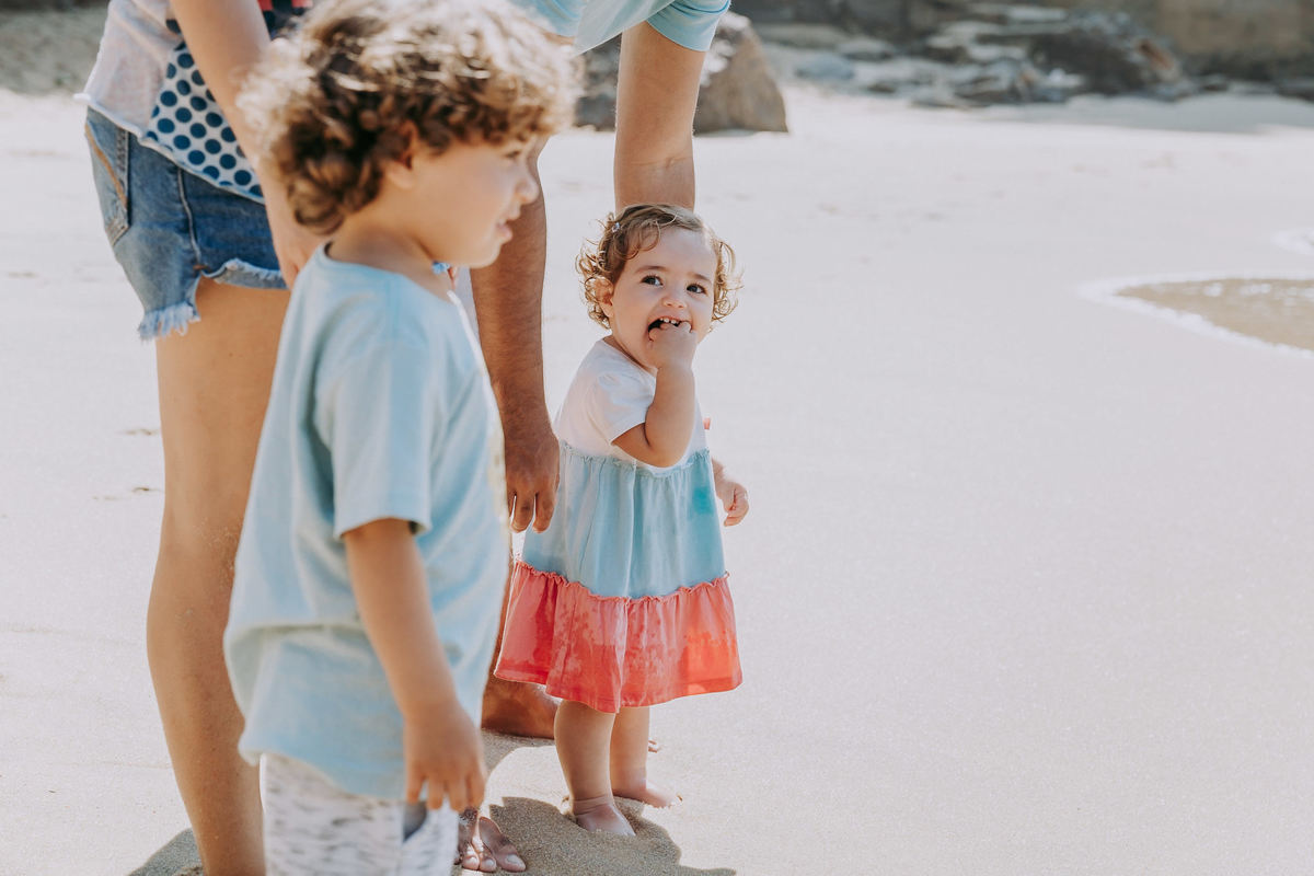 Fotografia de Família com imãos na praia vermelha com a irmã olhando pra câmera