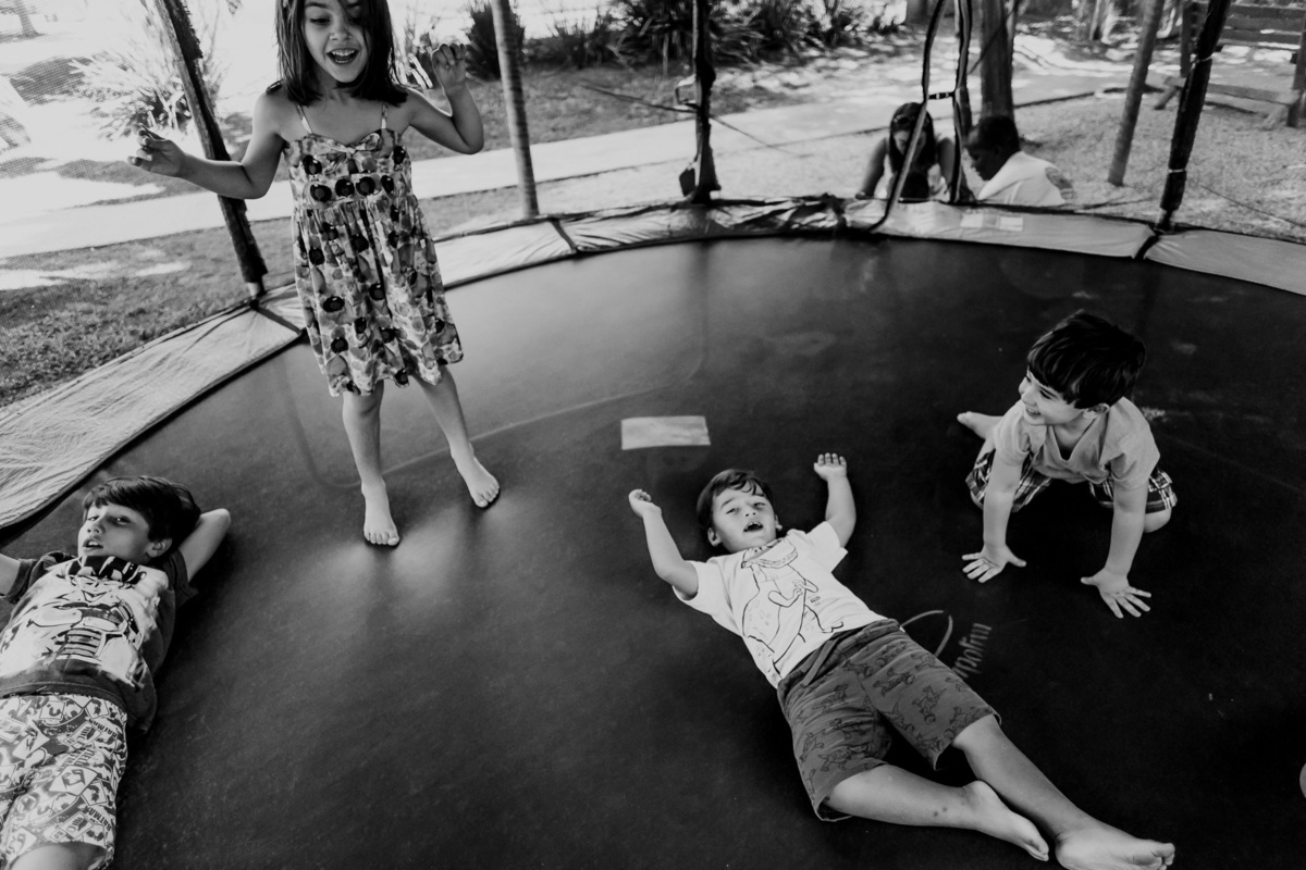 fotografia preto e branco de crianças se divertindo no pula pula alguns deitados outros pulando