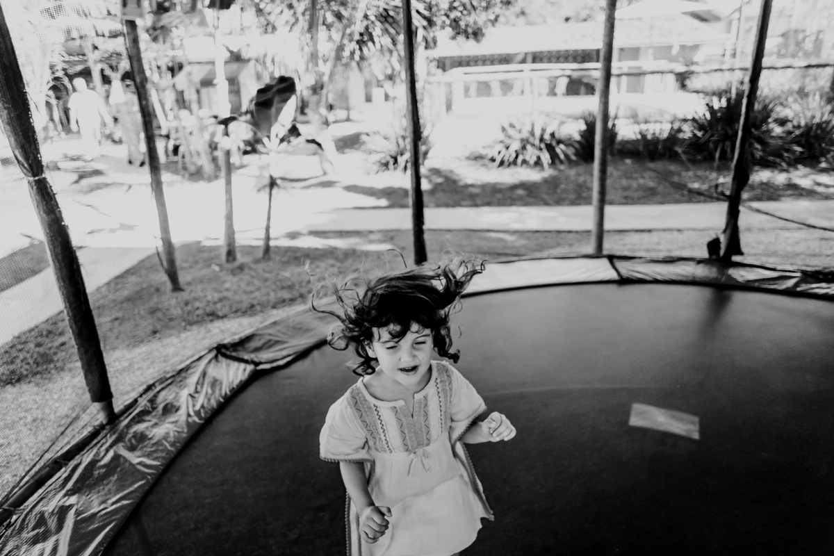 fotografia de menina de olhos fechados pulando no pula pula