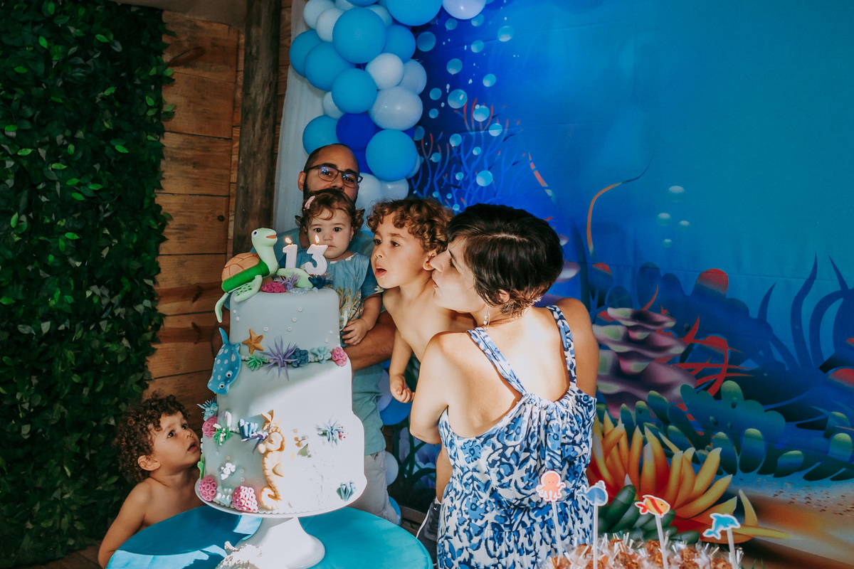 fotografia dos pais e aniversariantes assoprando a vela do bolo