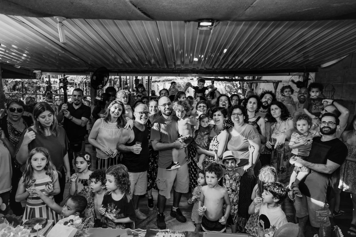 fotografia preto e branco de todos os convidados da festa infantil posando em frente a mesa do bolo