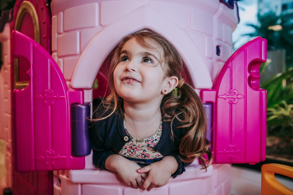 menina na janela de castelinho rosa de brinquedo