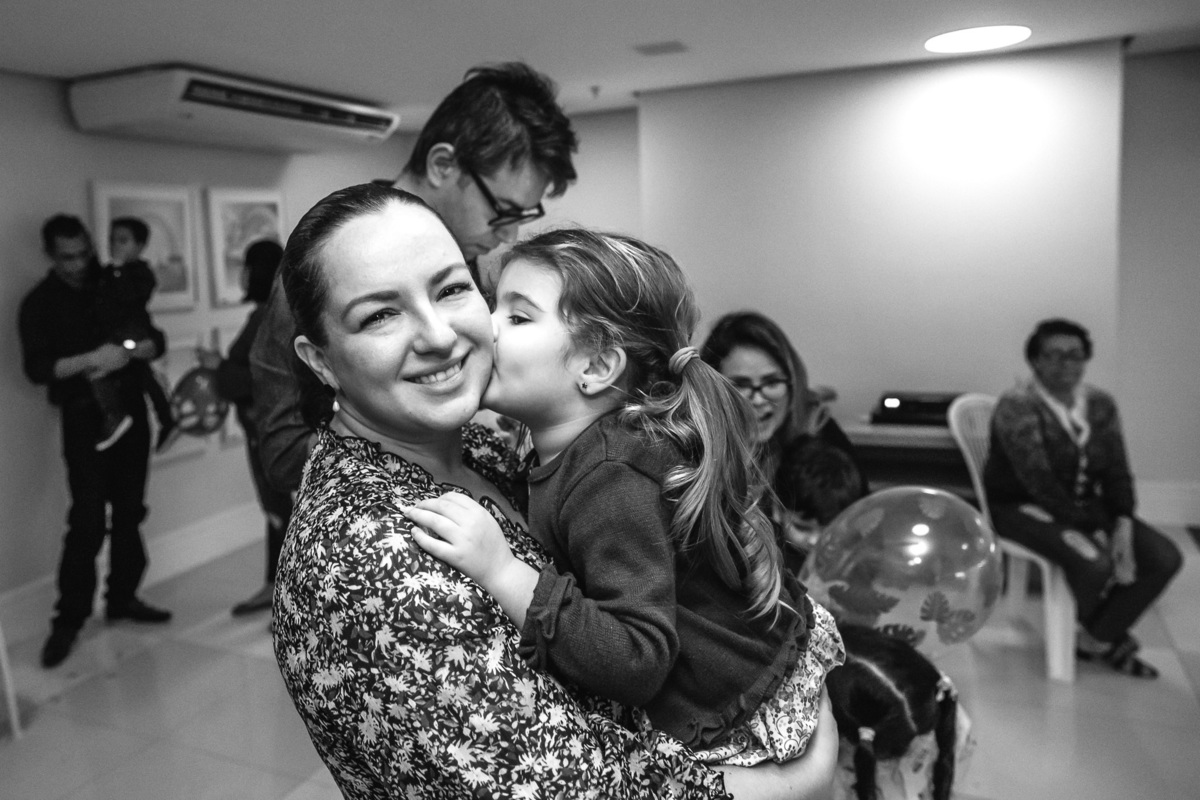 foto preto e branco em que filha beija o rosoto damae de forma carinhosa