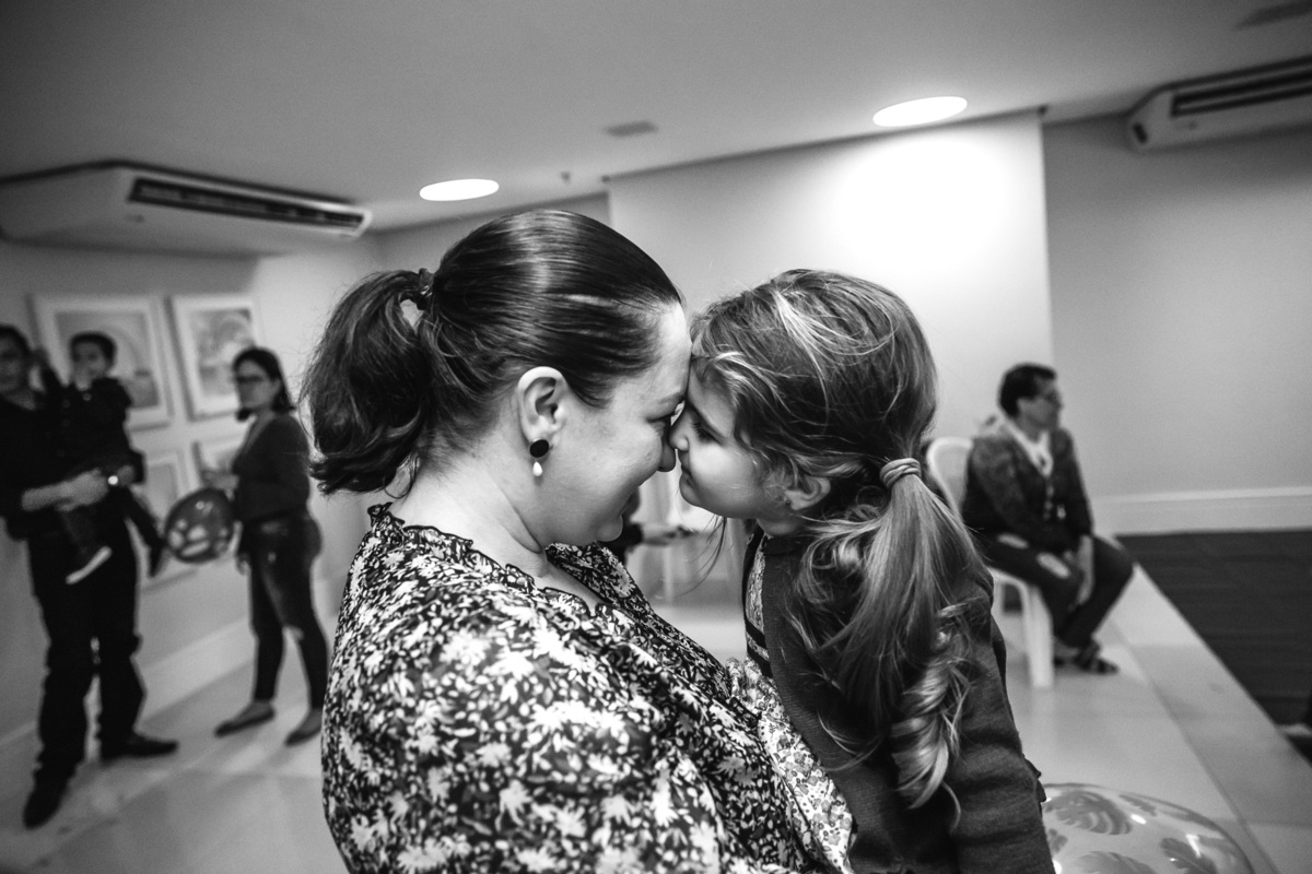 foto preto e branco em que filha está de rosto colado na mae fazendo chamego