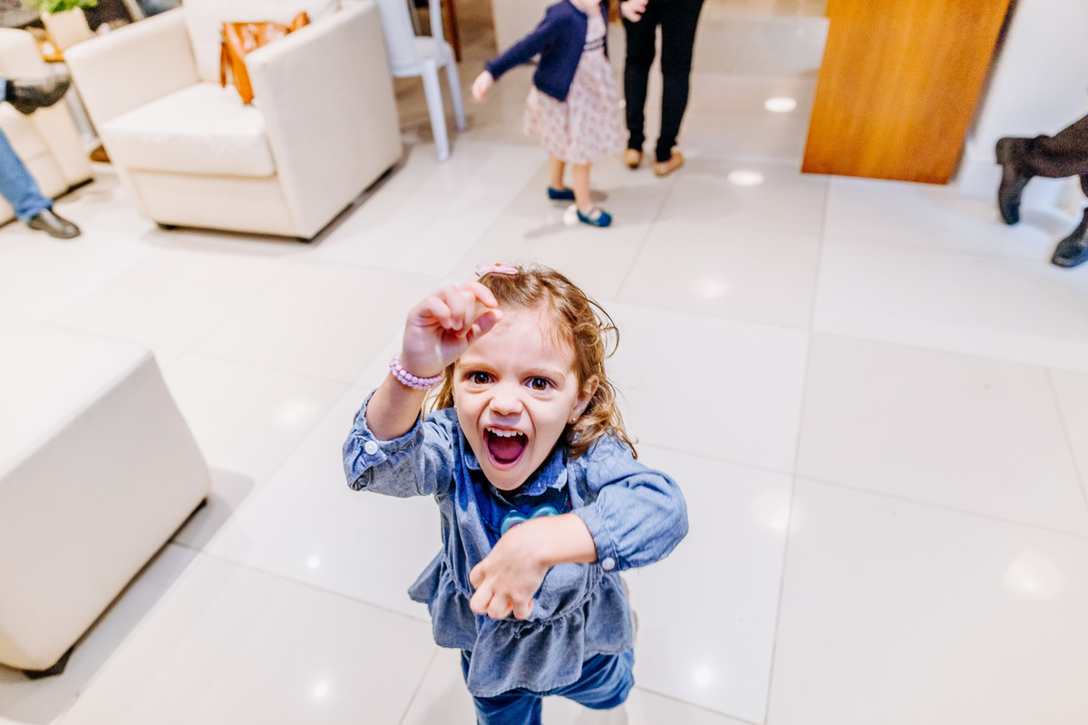 criança correndo pra cima de fotografa e fazendo careta pra camera