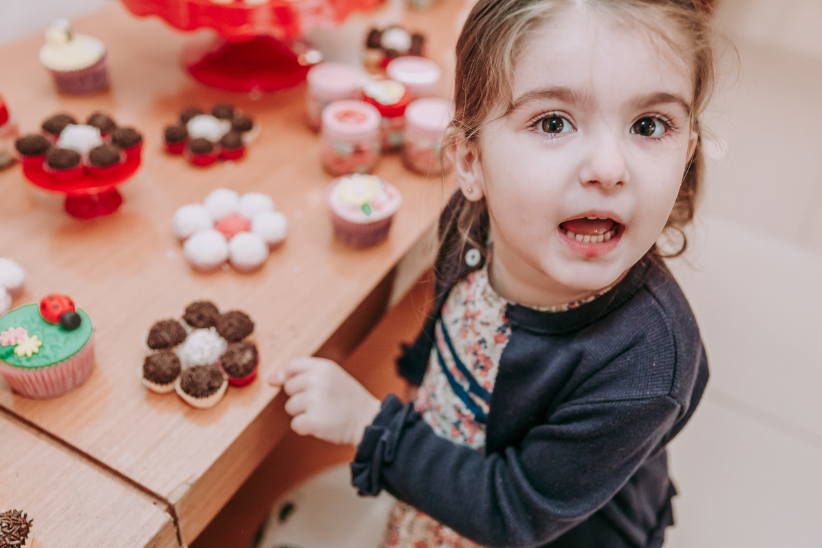 fotografia de criança apontando para brigadeiro e olhando para camera como se tivesse fazendo uma pergunta