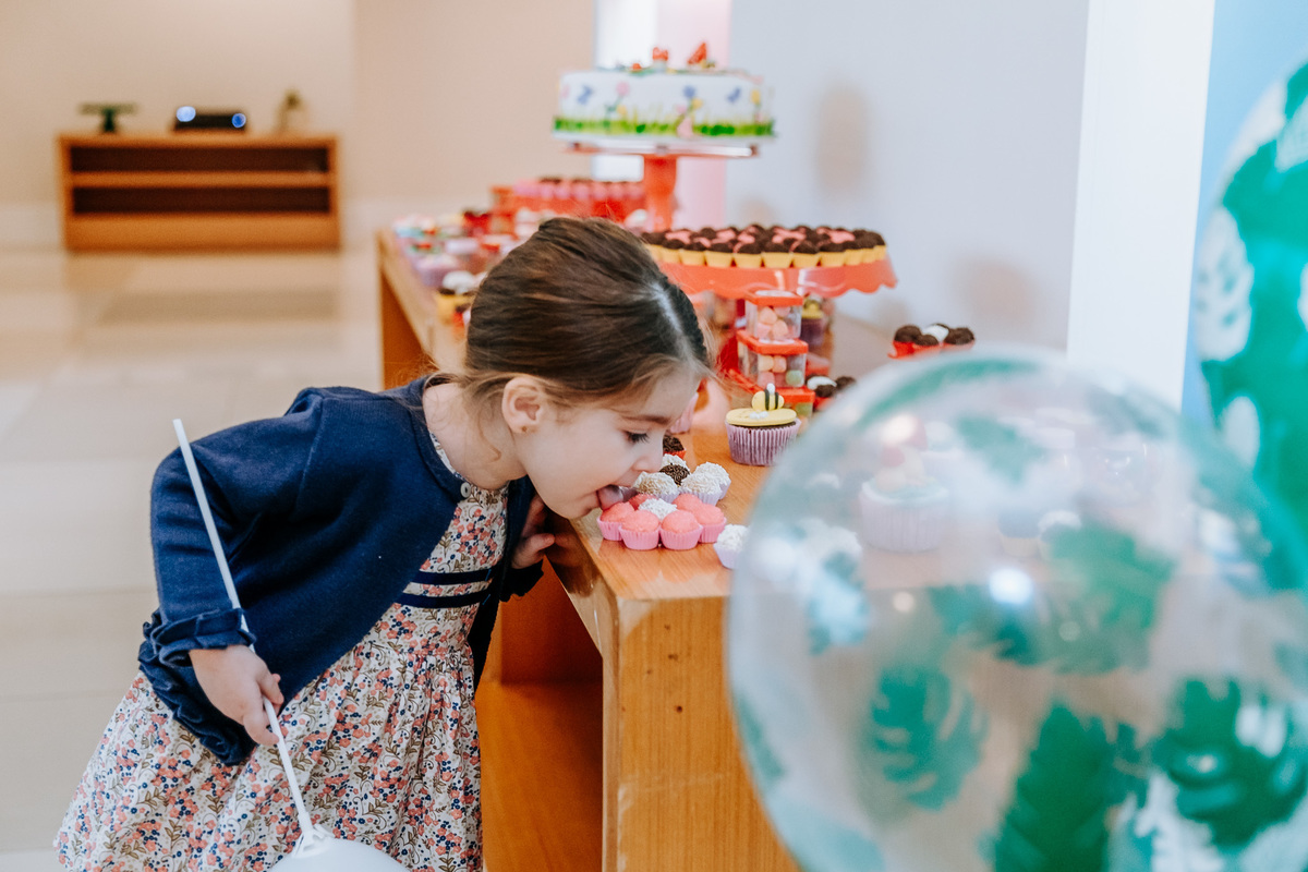 fotografia de criança lambendo um brigadeiro da mesa do bolo de sua festa de aniversario