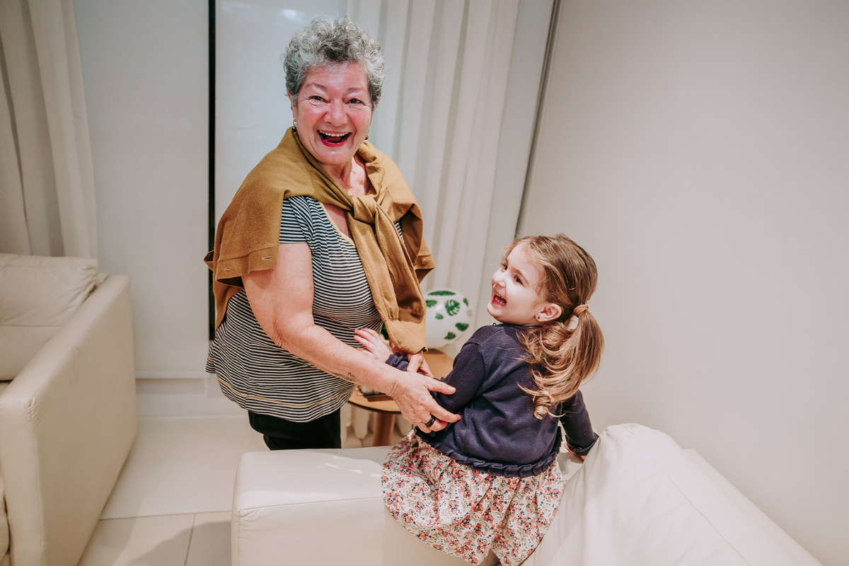 Fotografia de avó e neta sorrindo surpresas para a camera