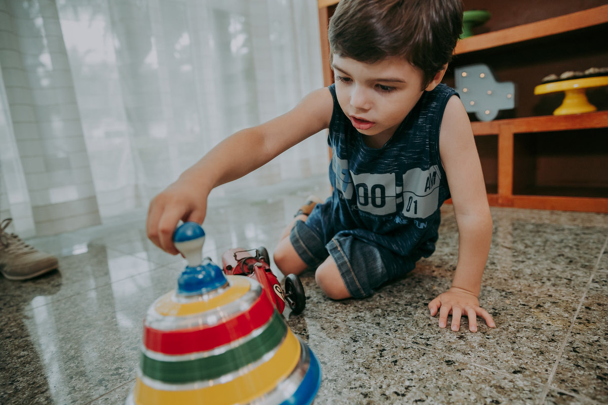 fotografia de menino sentado no chao girando peao