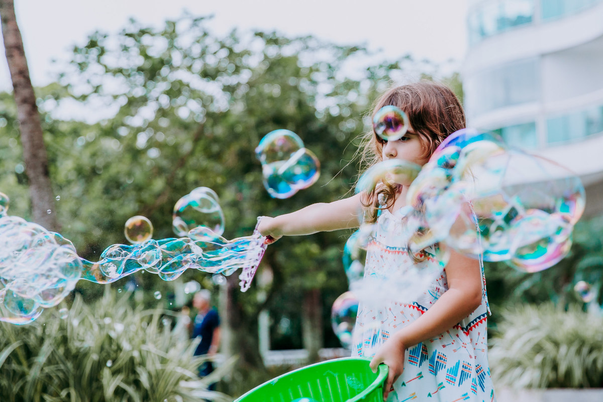 fotografia de menina brincando de fazer bolhas de sabao