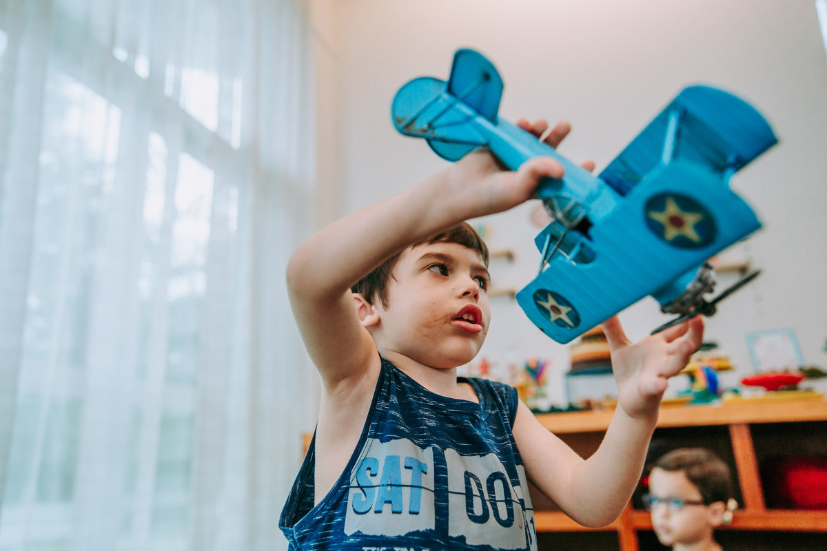 fotografia de menino brincando com aviao de lata azul
