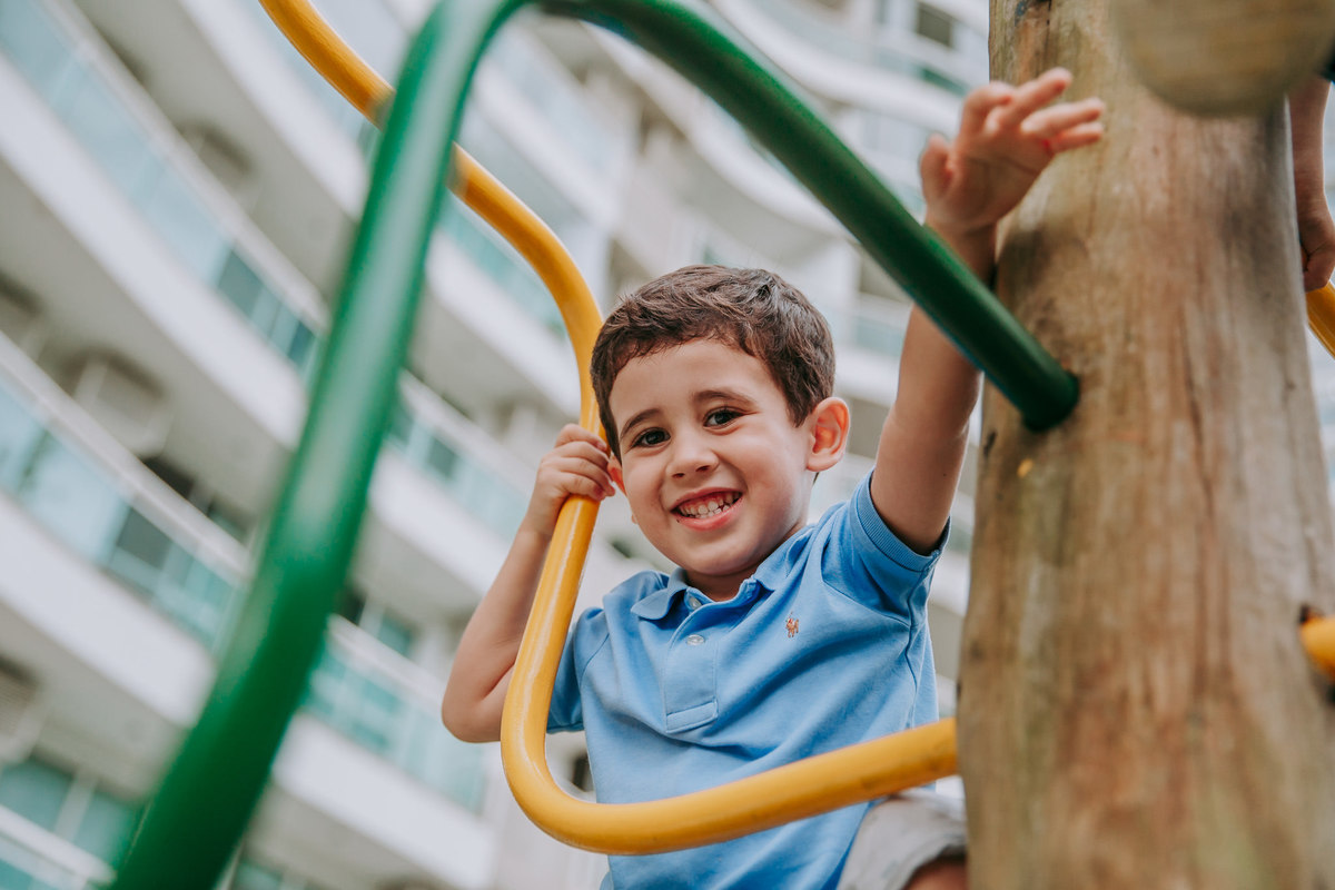 fotografia de menino sorrindo em brinquedo de escalar