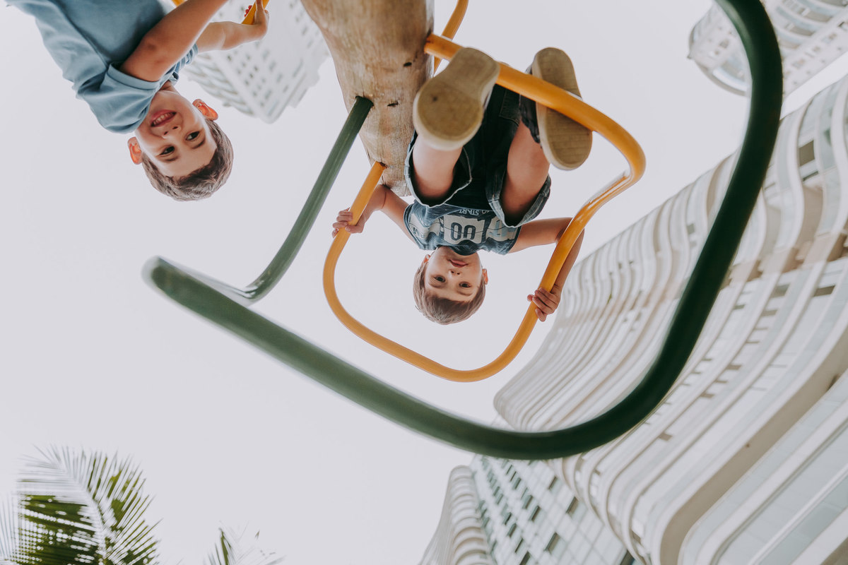 fotografia em contra-plonge de dois meninos subindo em brinquedo de escala em parquinho 