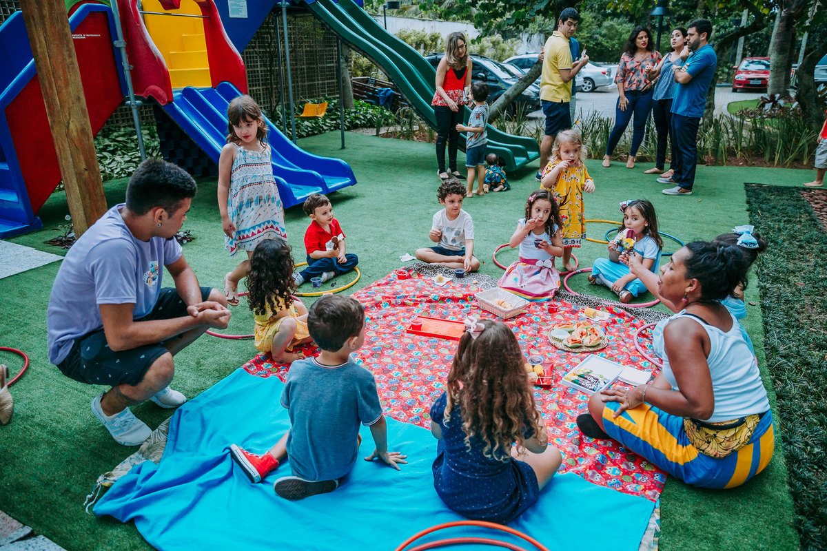 Fotografia de crianças sentadas em circulo lanchando em festa infantil