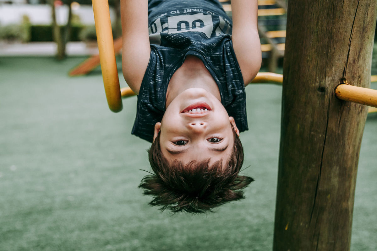fotografaai de menino de cabeça pra baixo em brinquedo de parquinho de condominio