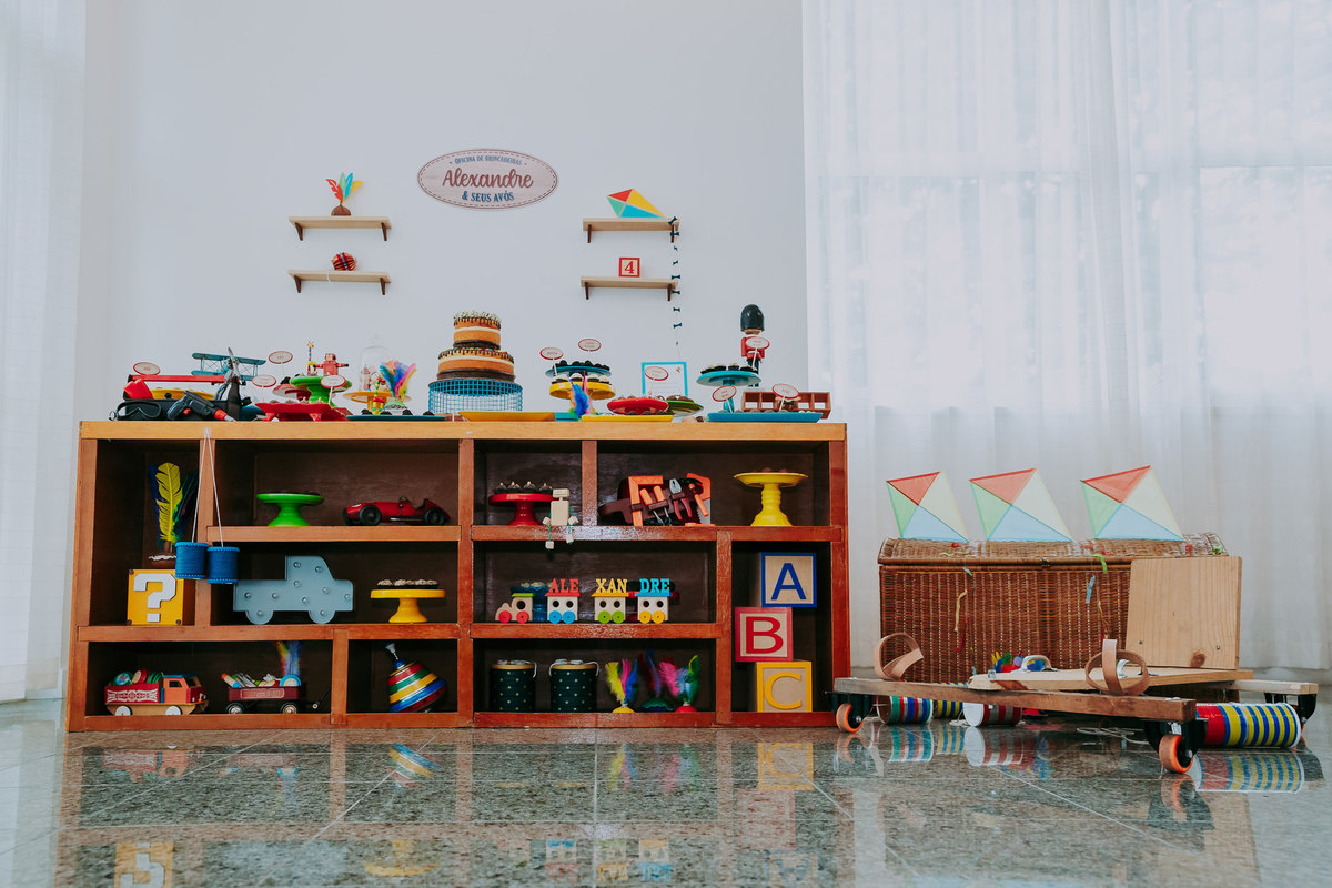 foto da mesa do bolo com tema oficina de brinquedos com carrinho de rolima pipae e diversos brinquedos antigos