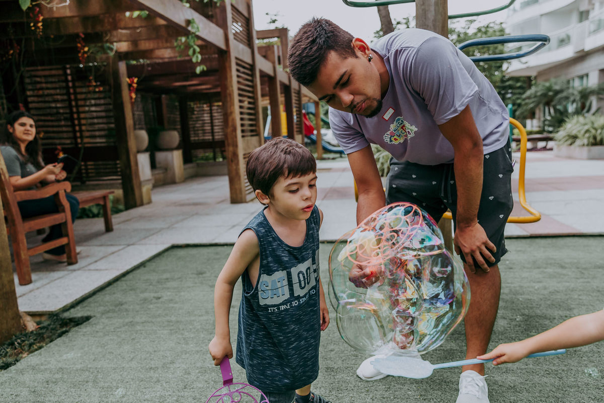 fotografia de menino assoprando bola de sabao gigante durante recreacao em festa de aniversario