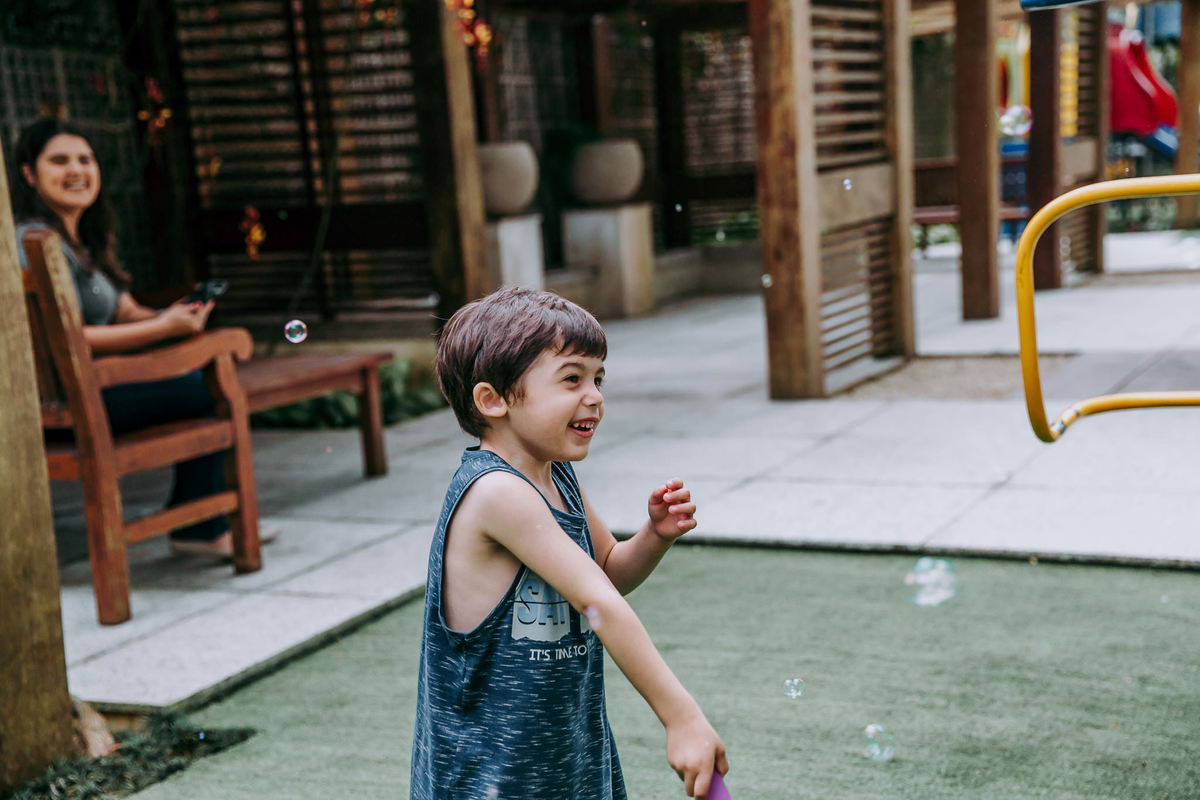 fotografia de menino sorrindo fazendfo bolha de sabao