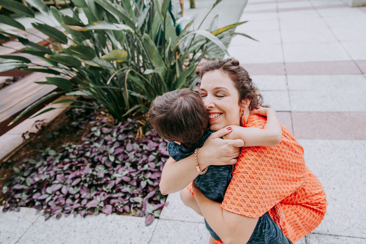 fotografia de mae agachada abraçando o filho