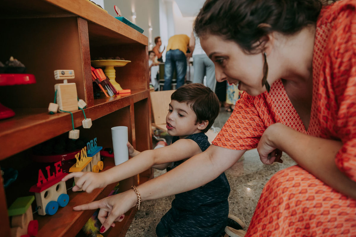 foto de mae agachada apontando para brinquedos da decoração da mesa do bolo
