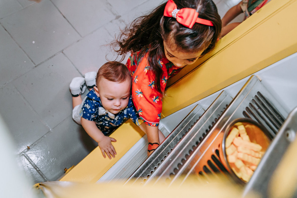 foto tirada do alto de duas crianças mexendo em uma geladeira que nao funciona