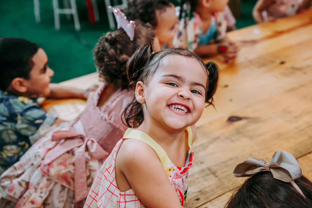 foto de criança com duas chiquinhas no cabelo sorrindo bem feliz para a camera