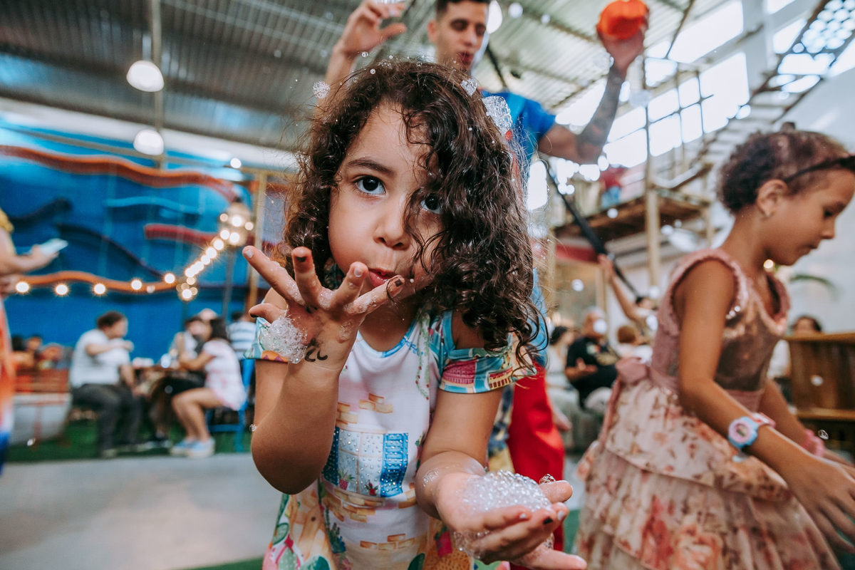 menina assopra espuma para acamera