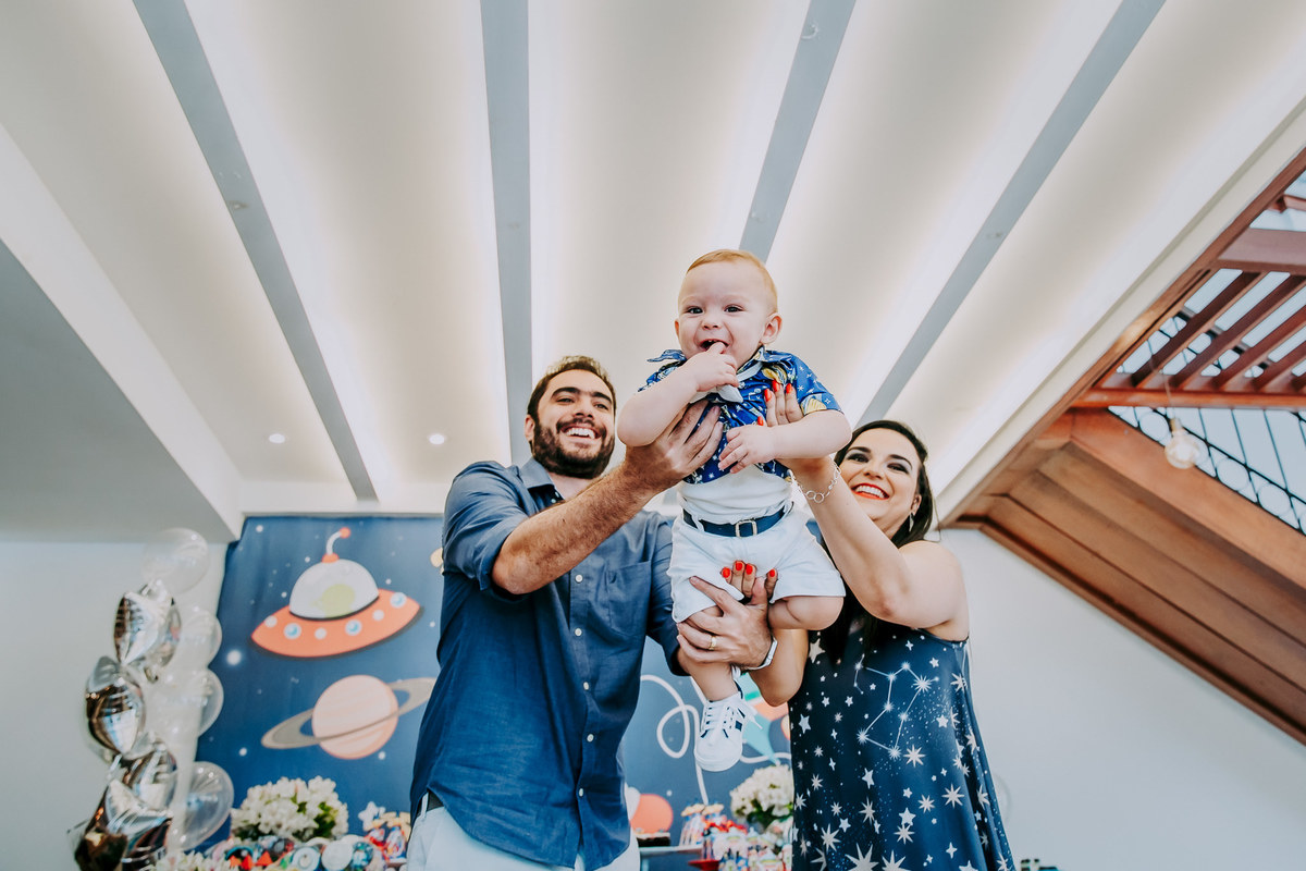 foto dos pais fazendo aviãozinho com os pais em seu aniversário