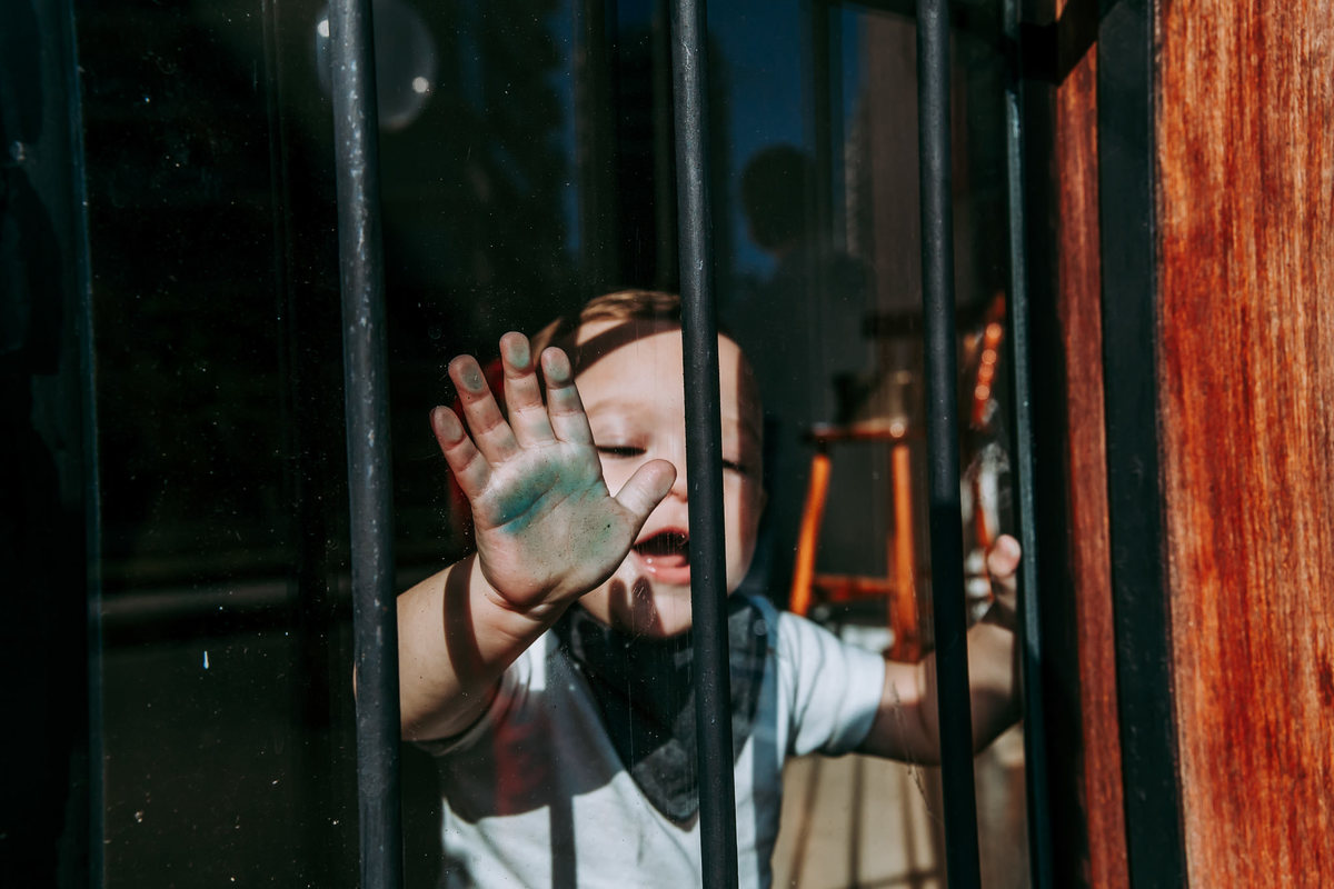criança batendo na porta de vidro com a mao toda verde