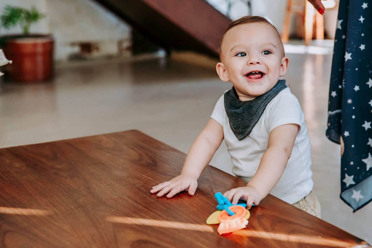 criança com as mãos apoiadas em mesa baixa