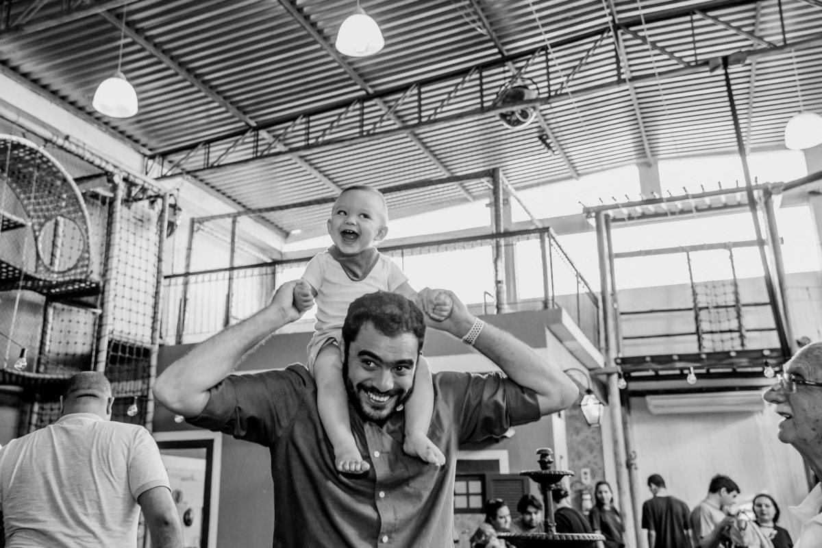 filho gargalhando na carcunda do pai em seu aniversário de 1 ano na vilarejo festas