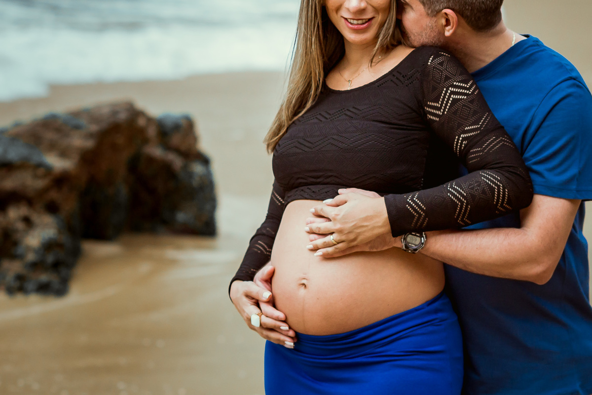 foto de casal abraçado acariciando a barriga da gestante e marido falando no ouvido dela