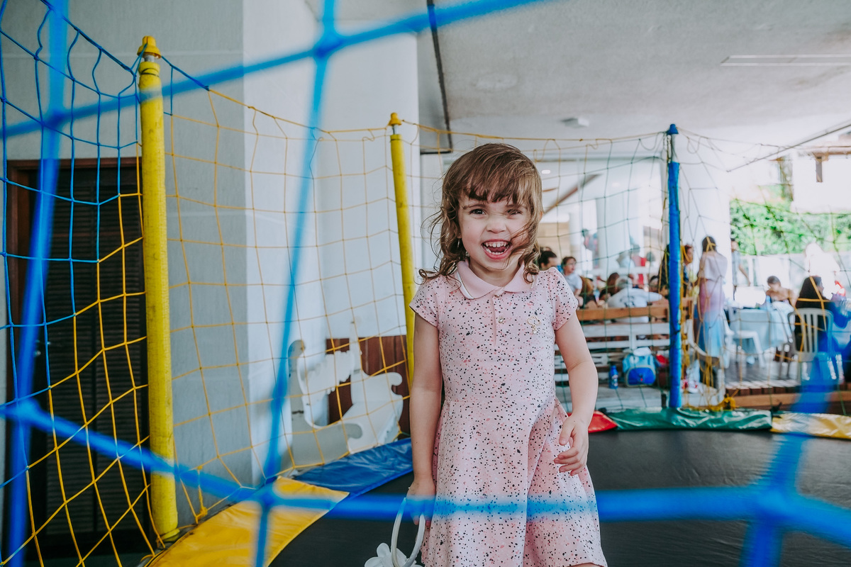 menina sorrindo através da rede do pula-pula