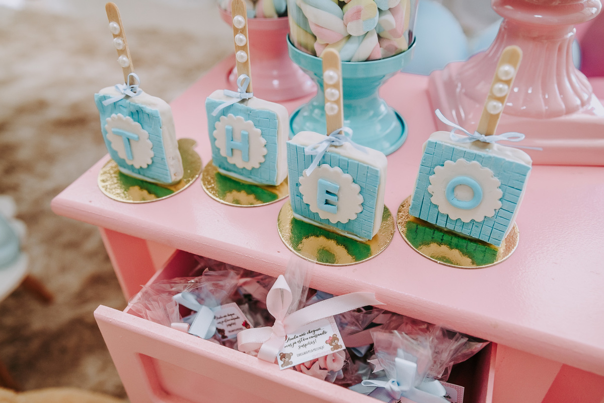 detalhe de decoracao de chá revelacao pirulitos azuis sobre uma mesa com gaveta rosa